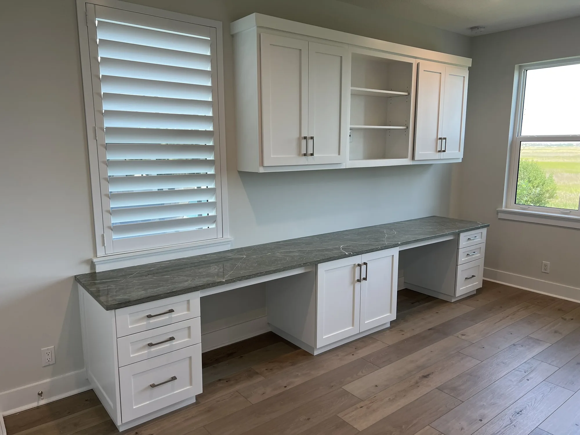 White wall-length office cabinetry with a stone worktop
